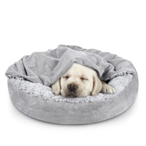 Sleeping puppy under a blanket in a gray dog bed