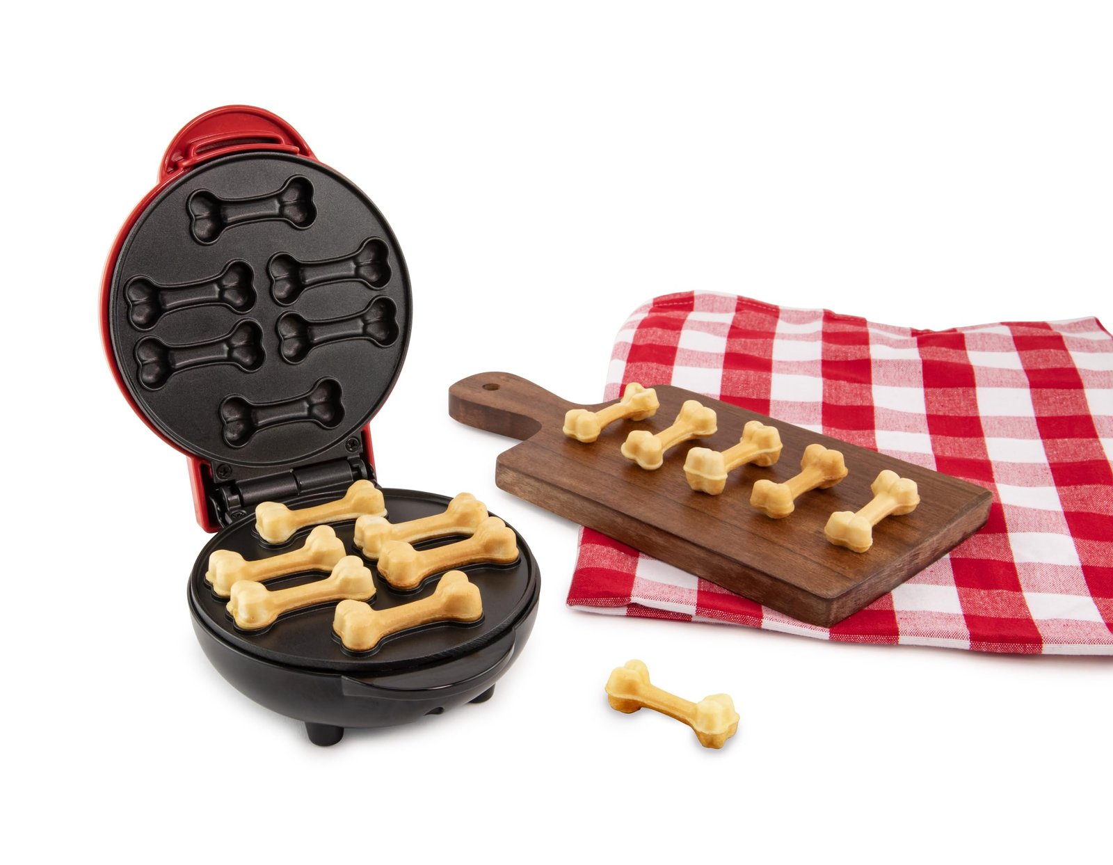 Dog bone-shaped waffle maker with waffles on a cutting board and red checkered cloth