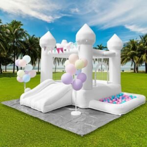 White inflatable castle with slide, balloons, and ball pit on green grass